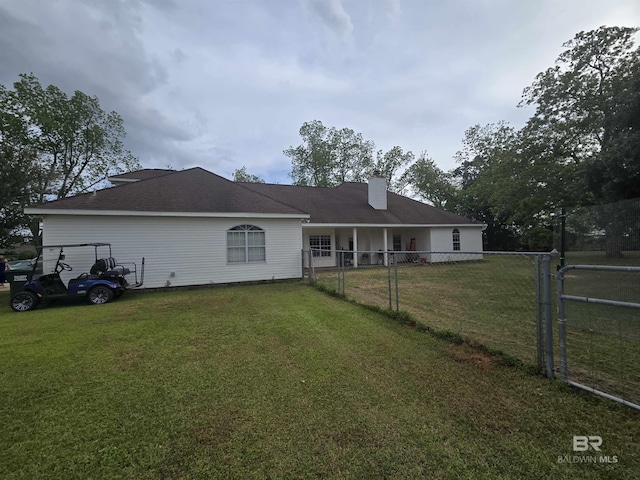 back of property featuring a lawn, a chimney, and fence