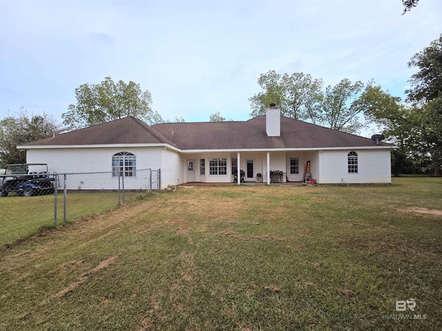 rear view of house with fence, a chimney, and a yard