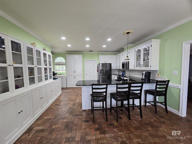 kitchen with crown molding, a peninsula, stainless steel appliances, and glass insert cabinets