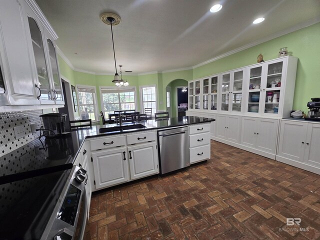 kitchen featuring white cabinetry, a sink, dark countertops, stainless steel appliances, and arched walkways