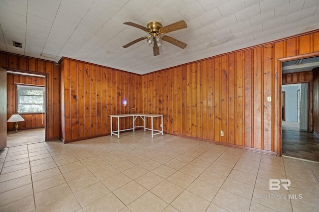 empty room with ornamental molding, wood walls, and ceiling fan