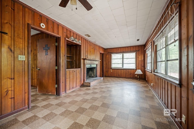 unfurnished living room with ceiling fan and wood walls