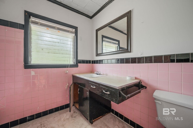 bathroom with toilet, tile patterned floors, tile walls, vanity, and ornamental molding