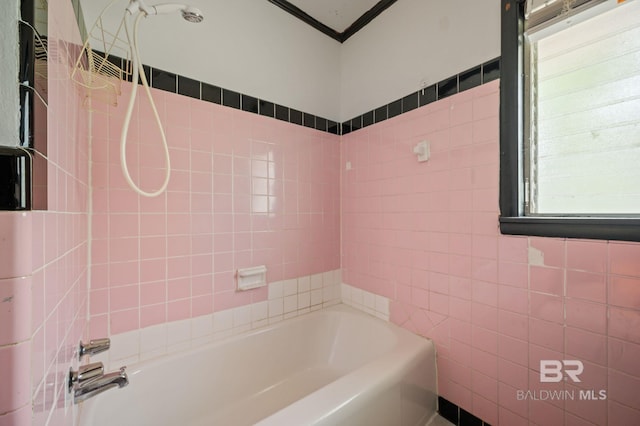 bathroom with tile walls, ornamental molding, and tiled shower / bath