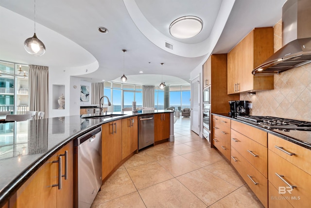 kitchen with visible vents, a sink, decorative backsplash, stainless steel appliances, and wall chimney exhaust hood