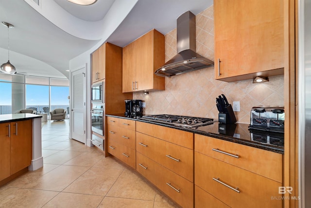 kitchen featuring open floor plan, light tile patterned floors, decorative backsplash, appliances with stainless steel finishes, and wall chimney exhaust hood