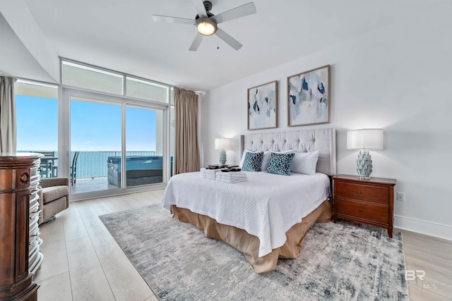 bedroom with light wood-style flooring, baseboards, access to exterior, and expansive windows