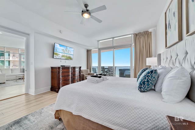 bedroom with a ceiling fan, access to outside, expansive windows, light wood finished floors, and baseboards