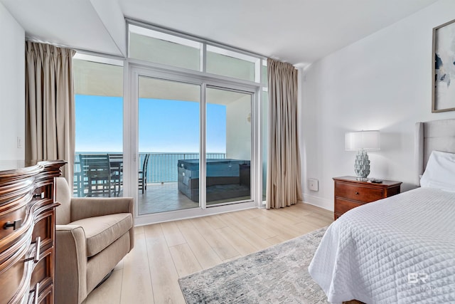 bedroom featuring a wall of windows, access to exterior, light wood-style floors, and baseboards