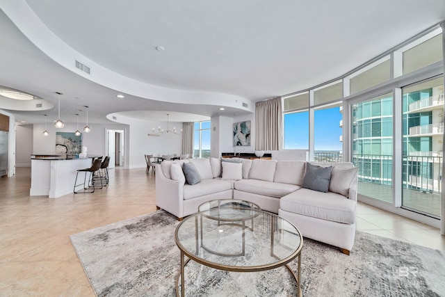 living area with a chandelier, visible vents, a wealth of natural light, and expansive windows