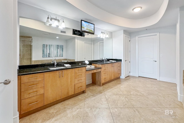 bathroom with visible vents, baseboards, two vanities, a raised ceiling, and a sink