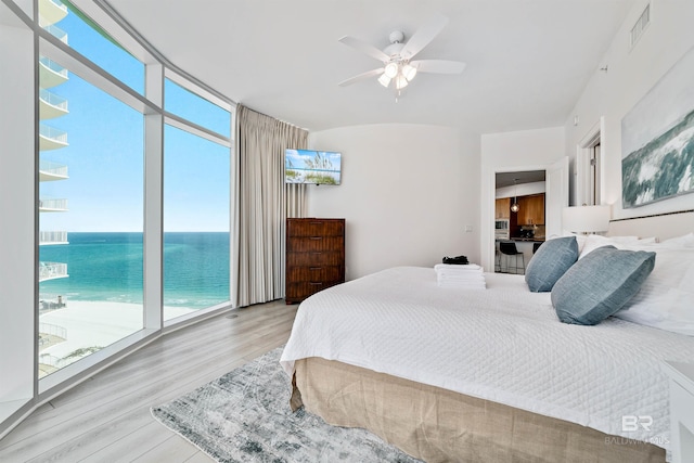 bedroom featuring light wood finished floors, visible vents, multiple windows, and a wall of windows