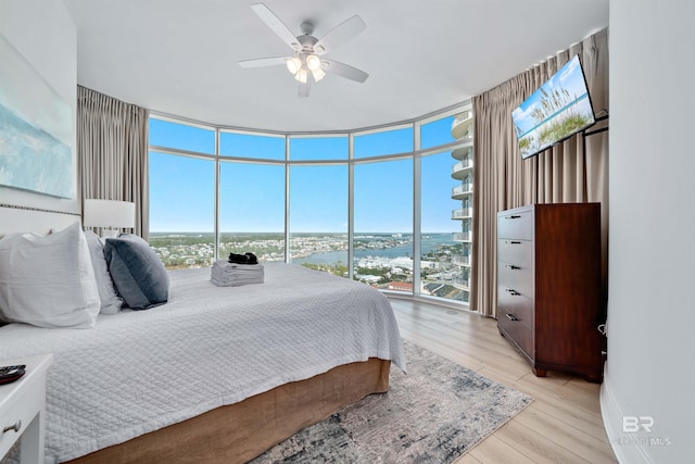 bedroom featuring light wood-type flooring, ceiling fan, and floor to ceiling windows