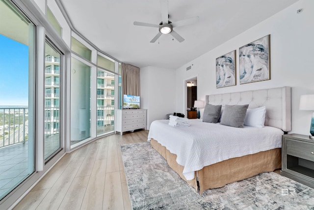 bedroom featuring visible vents, floor to ceiling windows, light wood-type flooring, a ceiling fan, and access to outside