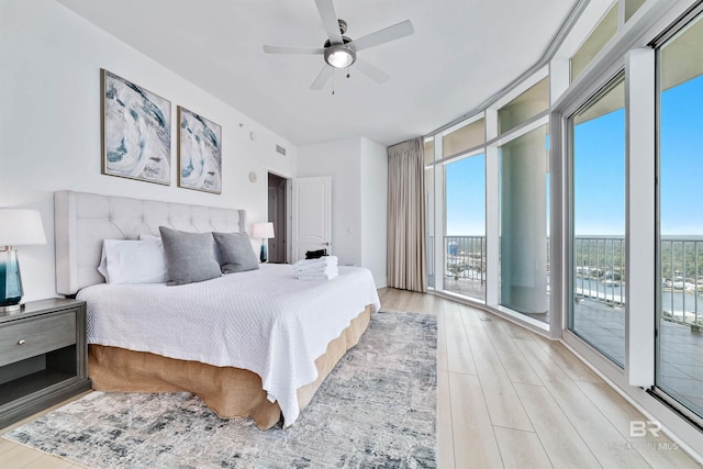 bedroom featuring expansive windows, access to exterior, a ceiling fan, and light wood finished floors