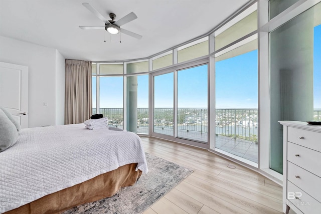 bedroom with access to exterior, multiple windows, wood finished floors, and expansive windows