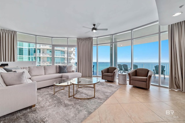 living area with tile patterned floors, floor to ceiling windows, plenty of natural light, and a water view