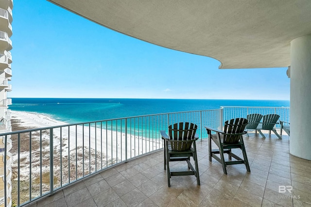 balcony with a water view and a view of the beach