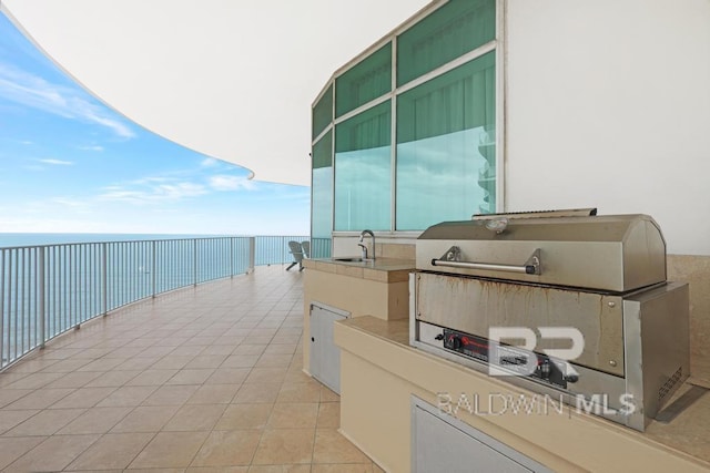 balcony with area for grilling, a water view, a grill, and a sink