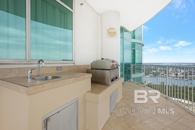 balcony with grilling area, exterior kitchen, a water view, and a sink