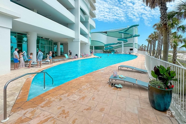 community pool with a water slide and a patio area