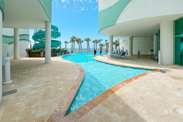 community pool with a patio area and a water slide