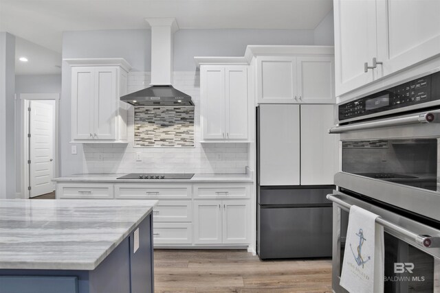 kitchen with white cabinets, wall chimney exhaust hood, and appliances with stainless steel finishes