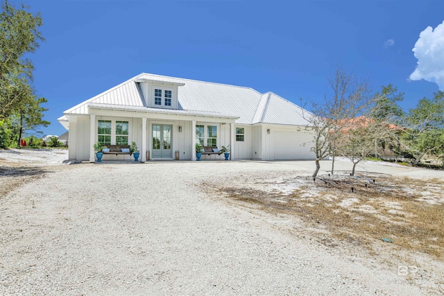 view of front of home featuring covered porch, a garage, and french doors