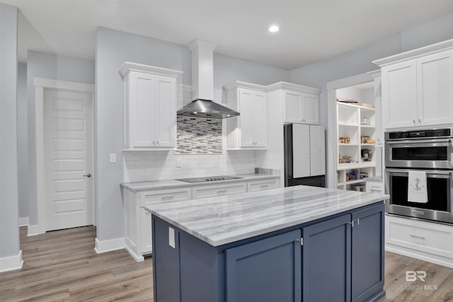 kitchen with white cabinets, wall chimney exhaust hood, black electric stovetop, and fridge