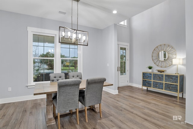 dining area with wood-type flooring and an inviting chandelier