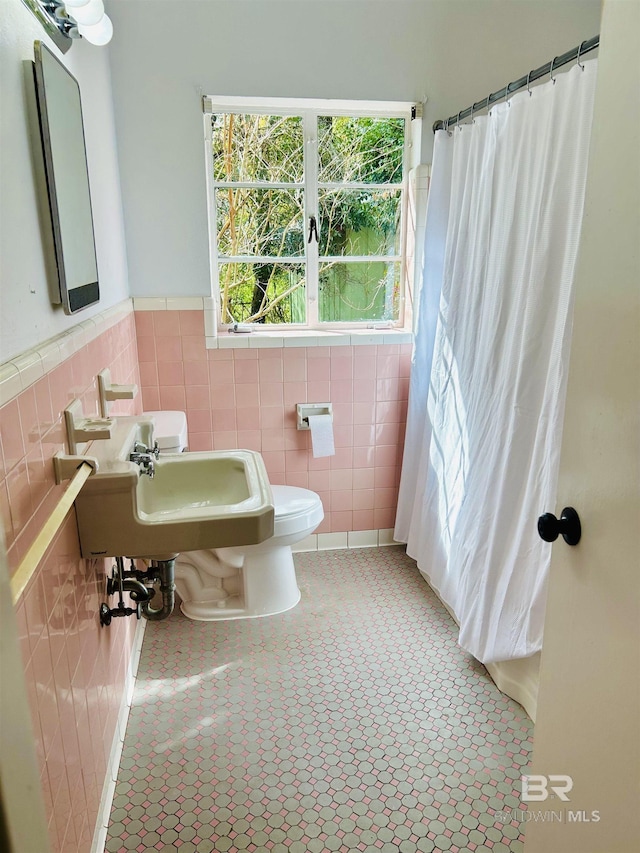 bathroom with tile walls, sink, curtained shower, and toilet