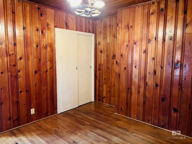 interior space featuring wood-type flooring, a chandelier, and wood walls