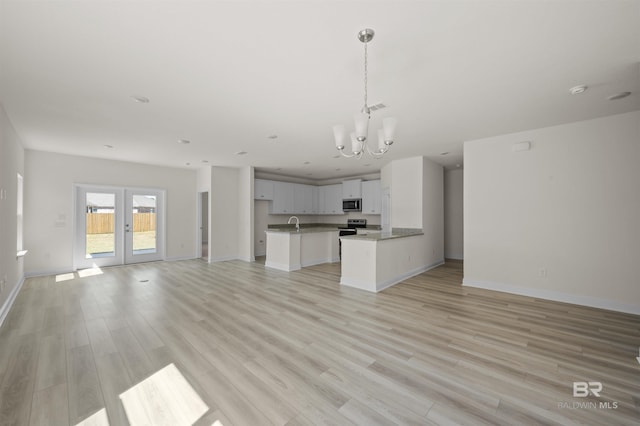 kitchen featuring open floor plan, stainless steel microwave, french doors, and light wood finished floors