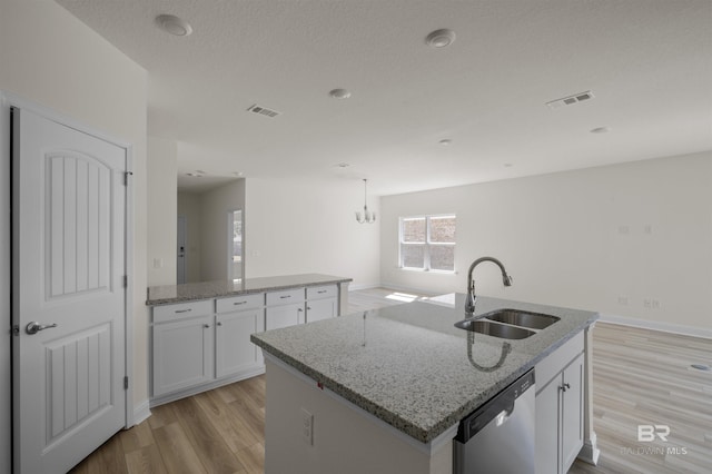 kitchen with dishwasher, an island with sink, light wood-type flooring, white cabinetry, and a sink