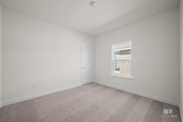 empty room featuring light carpet and baseboards