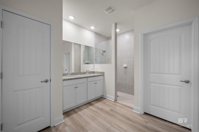 full bath featuring recessed lighting, visible vents, vanity, wood finished floors, and walk in shower
