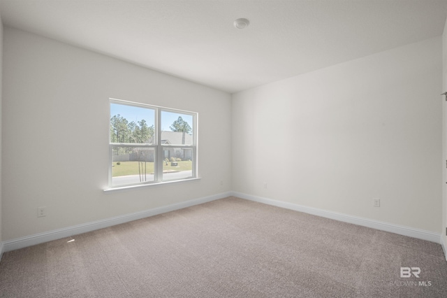 unfurnished room featuring light colored carpet and baseboards