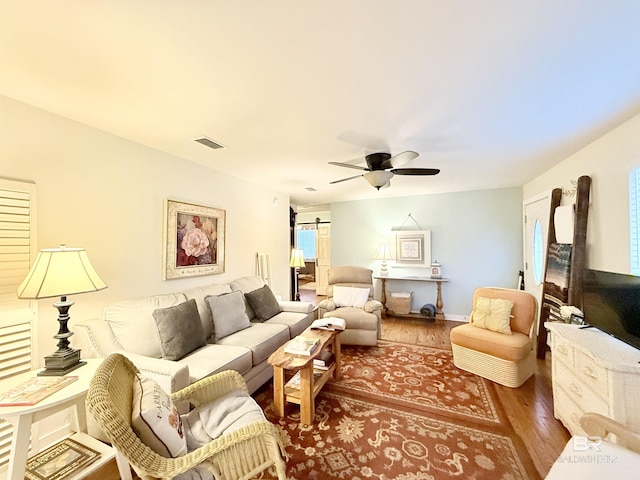 living area with visible vents, wood finished floors, and a ceiling fan