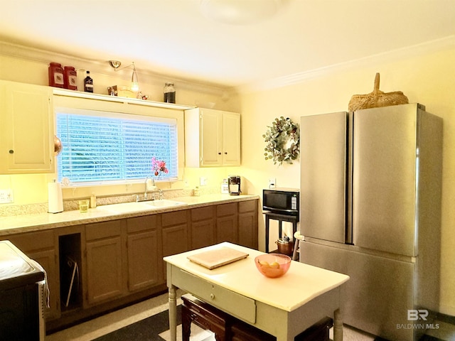 kitchen featuring a sink, freestanding refrigerator, white cabinets, crown molding, and black microwave