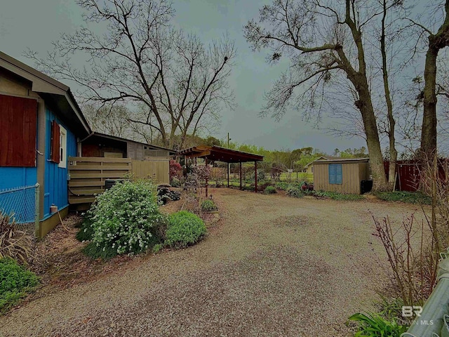 view of yard with driveway, a storage shed, an outdoor structure, and fence