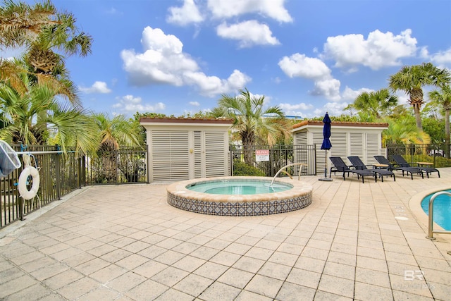 community pool with fence, a hot tub, and a patio area