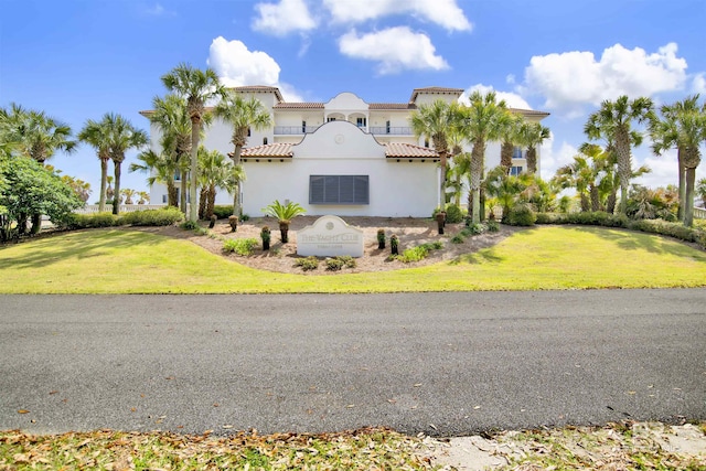 view of front facade with stucco siding, a tile roof, and a front yard