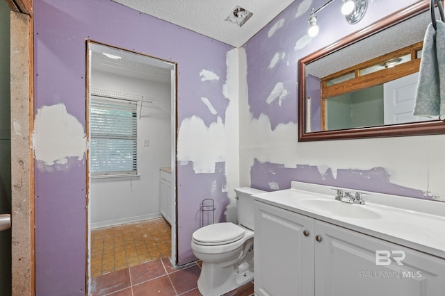 bathroom featuring tile patterned flooring, vanity, a textured ceiling, and toilet