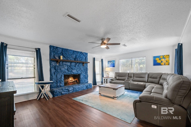 living room with a textured ceiling, ceiling fan, a healthy amount of sunlight, and dark wood-type flooring