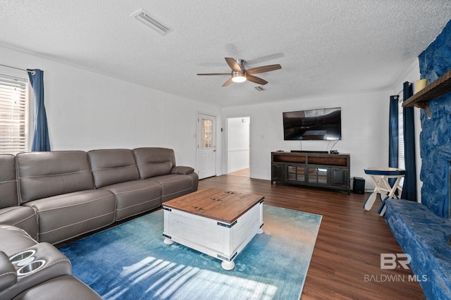 living room with a textured ceiling, dark hardwood / wood-style floors, and ceiling fan