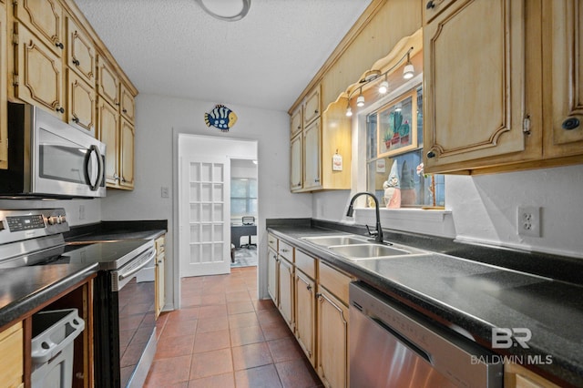 kitchen with sink, tile patterned flooring, a textured ceiling, and appliances with stainless steel finishes