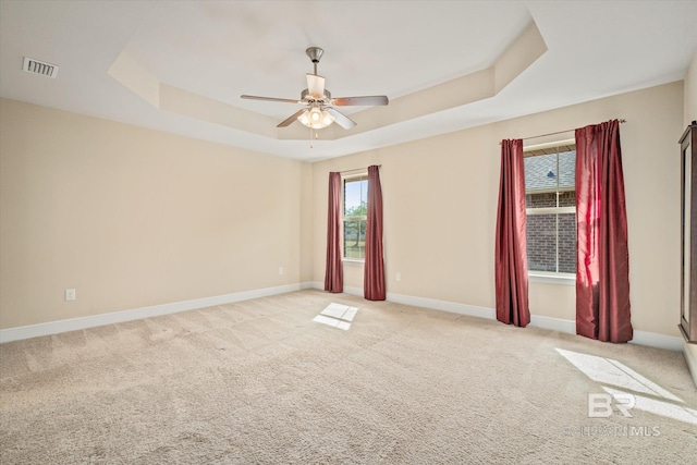 unfurnished room with a tray ceiling, ceiling fan, and light colored carpet