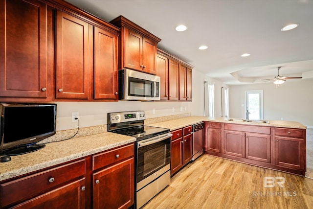 kitchen with sink, ceiling fan, light hardwood / wood-style floors, light stone counters, and stainless steel appliances