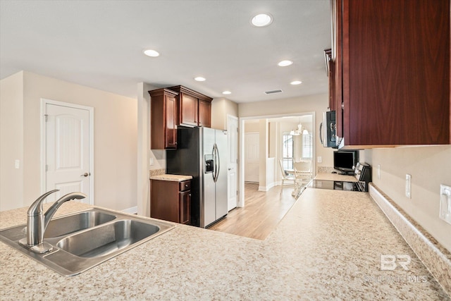 kitchen with stove, sink, stainless steel refrigerator with ice dispenser, and light hardwood / wood-style flooring