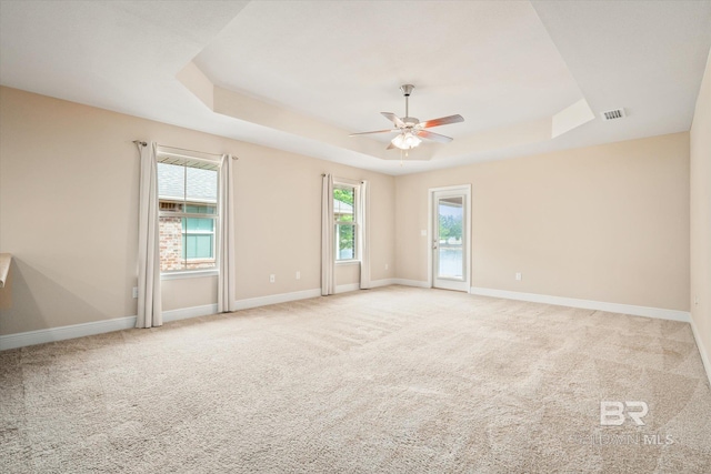 carpeted spare room with ceiling fan and a raised ceiling